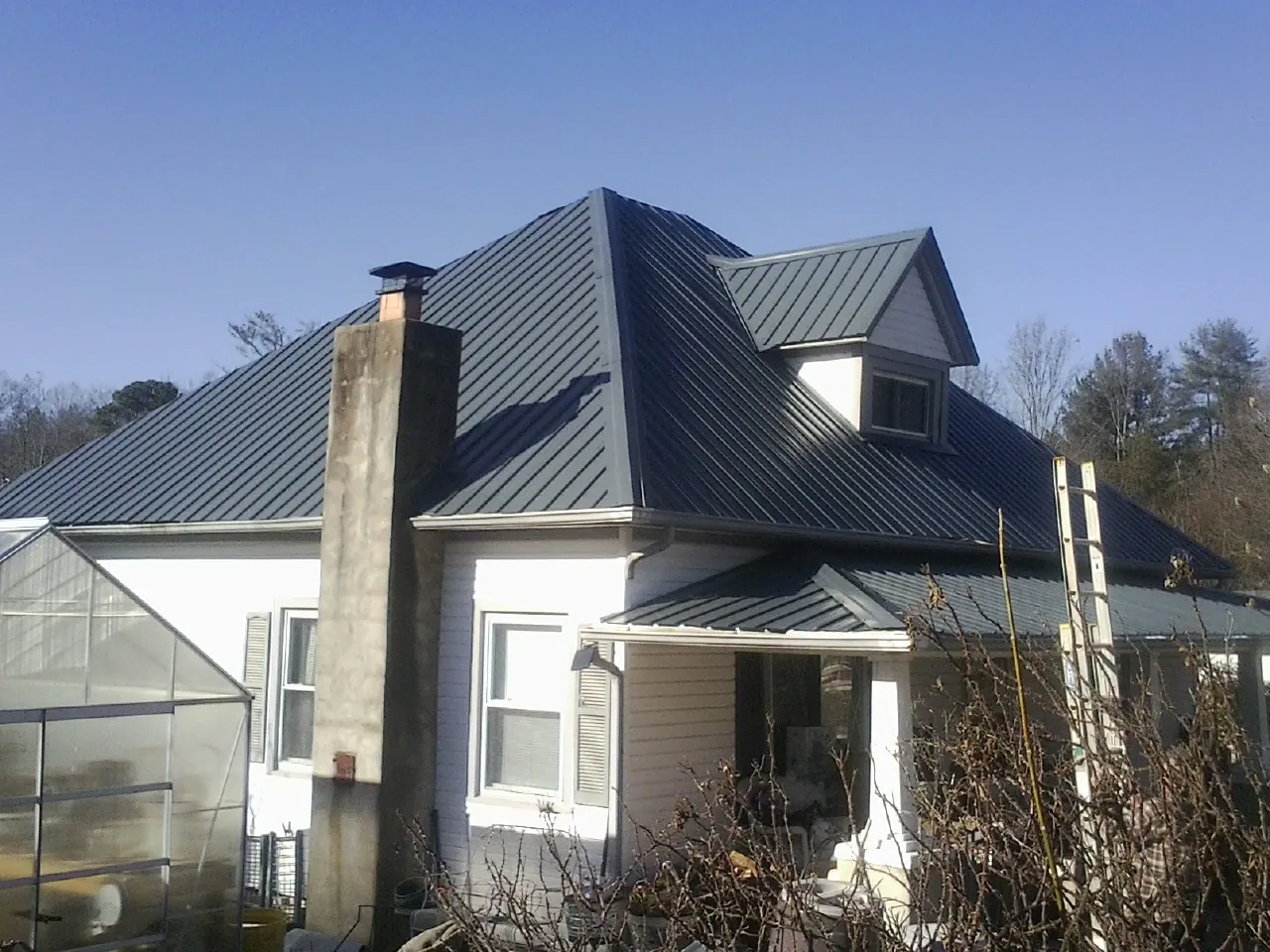 Dark blue standing seam metal roof on a white farmhouse with dormer — Slate & Tile Roof Repair by Roofing Brothers in Anna