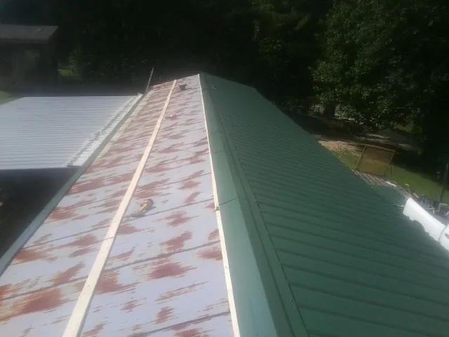 Old rusted panels beside newly installed green metal roofing — Wind Damage Roof Repair by Roofing Brothers in Anna