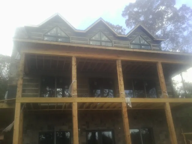 Dormers and porch framing on a large log home under construction — Roof Coating work by our crew in Anna