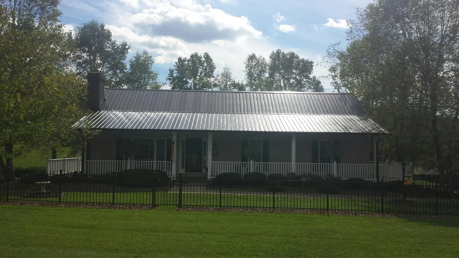 Gray metal roof on a brick ranch with a full width front porch — Gutter Guard Installation work by our crew in Anna