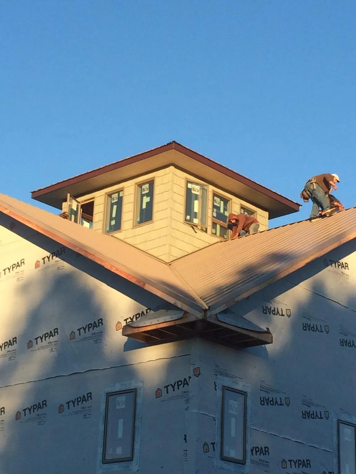 Roofers working around a rooftop cupola on a new metal roof at sunset — Roof Waterproofing in Anna by Roofing Brothers
